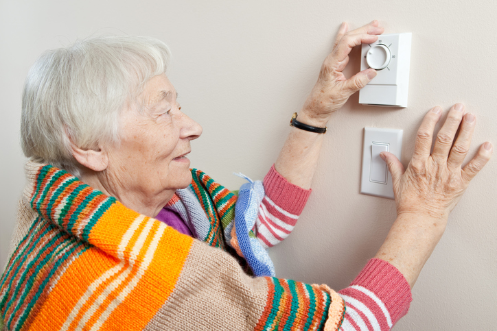 senior adjusting thermostat